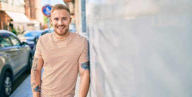 Genç İrlandalı gülümseyen mutlu adam şehrin duvarına yaslanıyor..