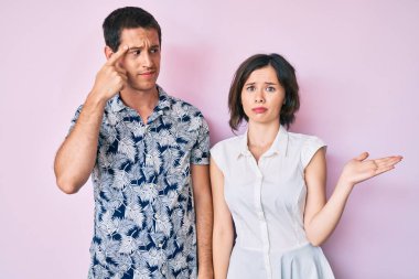 Gündelik giysiler giyen güzel bir çift, avuç içi açık fotokopi alanı gösterip, alnını işaret etmekten rahatsız oluyor. Bunu bir düşün.. 