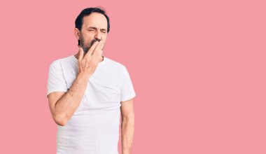 Sıradan tişörtler giyen orta yaşlı yakışıklı bir adam ağzıyla ağzını kapatmaktan sıkılmış. Huzursuz ve uykulu.. 