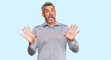 Orta yaşlı, gri saçlı, günlük kıyafetler giyen, korku ifadesinden korkan, dehşete düşmüş, elleri titreyen, şok içinde bağıran bir adam. panik konsepti. 