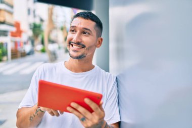 Şehrin duvarına yaslanmış dokunmatik ped kullanan genç bir İspanyol..