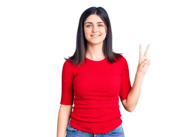 Gayri resmi tişört giyen genç ve güzel bir kız. Gülümsüyor ve kameraya göz kırpıyor. Zafer işareti yapıyor. İki numara.. 