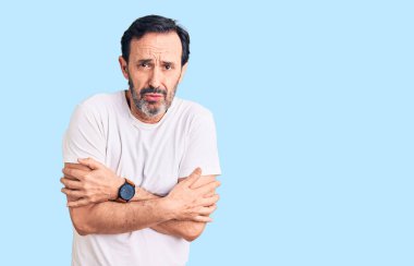 Orta yaşlı yakışıklı bir adam günlük tişört giyiyor. Kış soğuğu için titriyor ve donuyor. Yüzünde üzgün ve şok ifadesi var. 