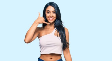 Güzel İspanyol kadın günlük kıyafetler giyip gülümsüyor telefonla el ve parmaklarıyla jest yapıyor telefonda konuşuyor gibi. iletişim kavramları. 