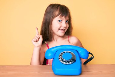 Masada uzun saçlı beyaz bir kız oturuyordu. Klasik bir telefonla gülümsüyordu. Bir fikir veya soruyla gülümsüyordu. 