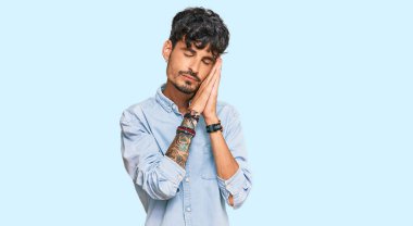 Gündelik kıyafetler giyen genç İspanyol adam uyur. Yorgun düşler kurar, ellerle poz verir, gözleri kapalı gülümserdi.. 