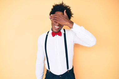 Yakışıklı Afro saçlı, şık giyinen, hippi görünümlü, gülümseyen ve yüzünde şaşkınlıktan gözleri kapayan Afro-Amerikan erkeği. kör kavram. 