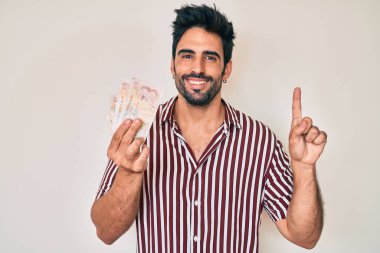 Yakışıklı, sakallı, krallığı elinde tutan yakışıklı bir adam. Bir fikir veya soruyla gülümsüyor. Mutlu bir yüzle işaret ediyor. 