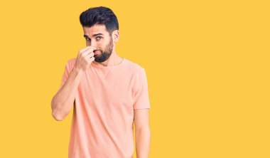 Sakallı, sıradan bir tişört giyen, pis ve iğrenç bir koku alan, nefesi burnunda olan genç ve yakışıklı bir adam. Kötü kokuyor. 