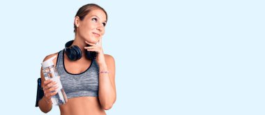 Spor kıyafetleri giyen genç, İspanyol bir kadın elinde su şişesi olan ciddi bir yüz ifadesi olan eli çenesinde soru soran, kafa karıştırıcı bir fikir hakkında düşünceli bir kadın. 