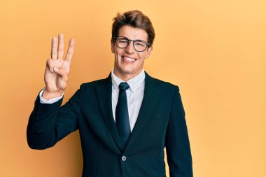 Yakışıklı, beyaz takım elbiseli ve kravatlı adam üç numaralı parmaklarıyla kendini beğenmiş ve mutlu gülümserken kendini gösteriyor.. 