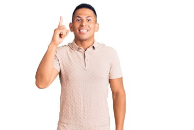 Gündelik kıyafetler giyen genç, yakışıklı, Latin bir adam başarılı bir fikri işaret ediyor. Heyecanlı ve mutlu. Bir numara.. 