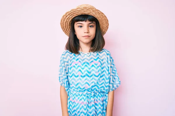 一个年轻的小女孩 穿着夏装 戴着一顶帽子 脸上带着严肃的表情 简单而自然地看着相机 — 图库照片