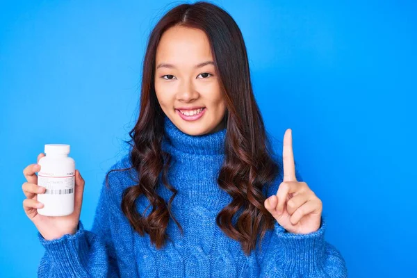 年轻美丽的中国姑娘拿着药丸微笑着 满脸喜形于色地指指点点 位居第一 — 图库照片