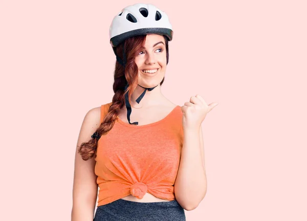 若いです美しいです女性身に着けています自転車ヘルメット笑顔で幸せな顔を見てと親指アップで側面を指して — ストック写真