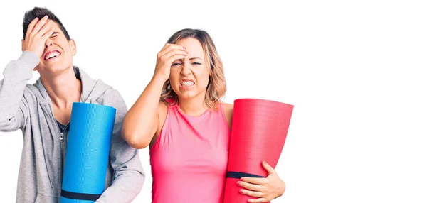 ヨガマットを保持している女性のカップルは強調し 頭の上に手でフラストレーション 驚きと怒っている顔 — ストック写真