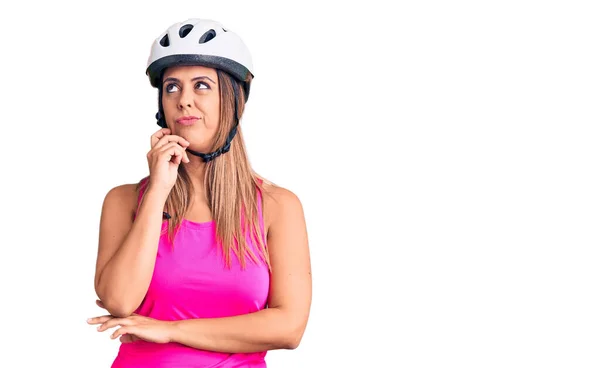 年轻美丽的女人戴着自行车头盔 严肃的面容 手托着下巴思考着问题 沉思着困惑的想法 — 图库照片