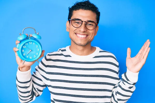 Joven Hombre Hispano Guapo Sosteniendo Despertador Celebrando Victoria Con Sonrisa — Foto de Stock