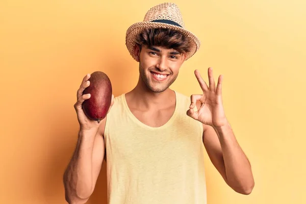 Joven Hombre Hispano Con Sombrero Sosteniendo Mango Haciendo Signo Con — Foto de Stock