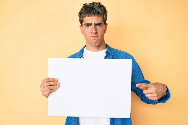 Joven Hombre Guapo Sosteniendo Blanco Banner Vacío Escéptico Nervioso Frunciendo — Foto de Stock