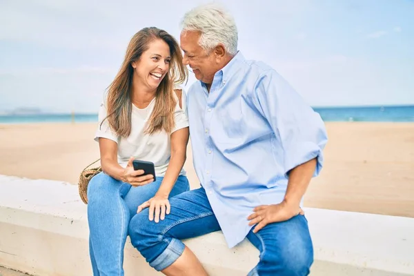 Pareja Hispana Mediana Edad Usando Teléfono Inteligente Sentado Banco Playa —  Fotos de Stock