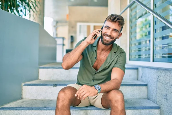 Ung Latinamerikansk Man Ler Glad Med Smartphone Sitter Trappor — Stockfoto