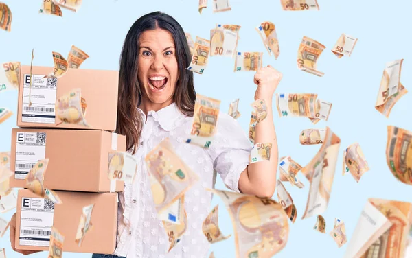 Young Beautiful Brunette Woman Holding Delivery Cardboard Package Screaming Proud — Stock Photo, Image