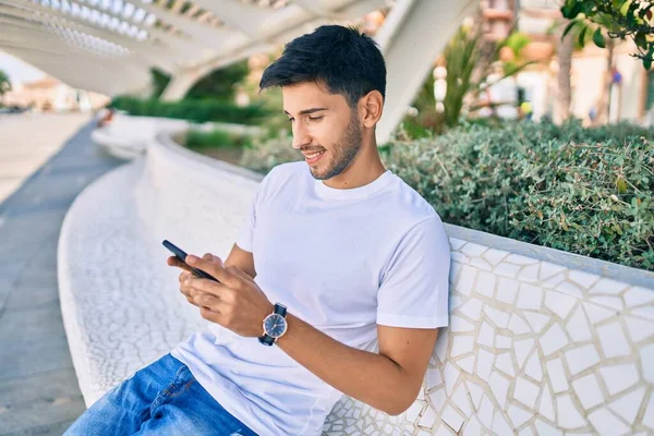 Joven Latino Sonriendo Feliz Usando Smartphone Sentado Banco —  Fotos de Stock