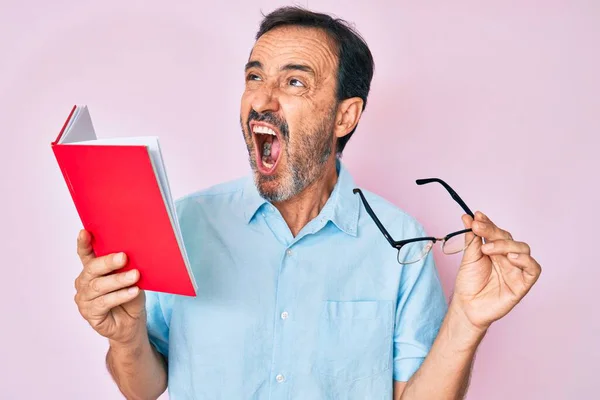 Homem Hispânico Meia Idade Lendo Livro Segurando Óculos Irritado Louco — Fotografia de Stock