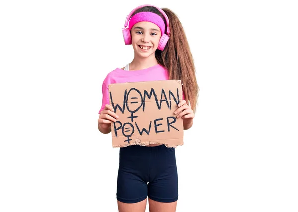 可爱的惊慌失措的小女孩 身穿运动服 手持耳机 高举女权运动旗帜 站在那里 面带微笑 露出自信的笑容 露出牙齿 — 图库照片