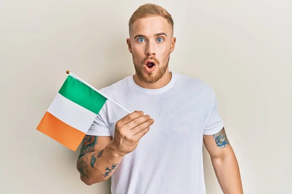 Νεαρός Καυκάσιος Που Κρατάει Ιρλανδική Σημαία Φοβισμένος Και Έκπληκτος Ανοιχτό — Φωτογραφία Αρχείου