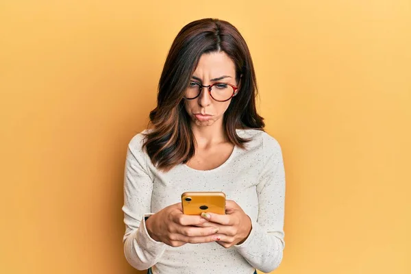 Mladá Brunetka Používá Smartphone Přes Žluté Pozadí Deprese Starosti Úzkost — Stock fotografie