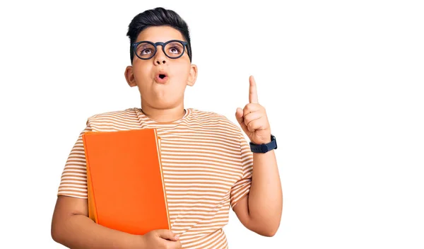 Niño Pequeño Sosteniendo Libro Con Gafas Asombrado Sorprendido Mirando Hacia —  Fotos de Stock