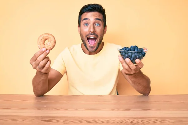 Νεαρός Ισπανόφωνος Τρώει Πρωινό Κρατώντας Ντόνατ Και Βατόμουρα Γιορτάζοντας Τρελά — Φωτογραφία Αρχείου