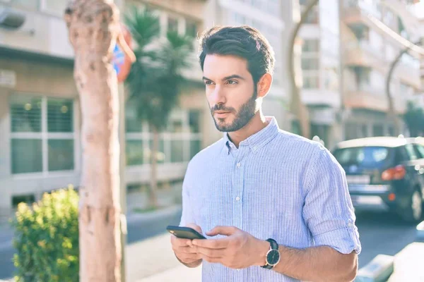 Joven Hispano Con Expresión Seria Usando Smartphone Ciudad —  Fotos de Stock