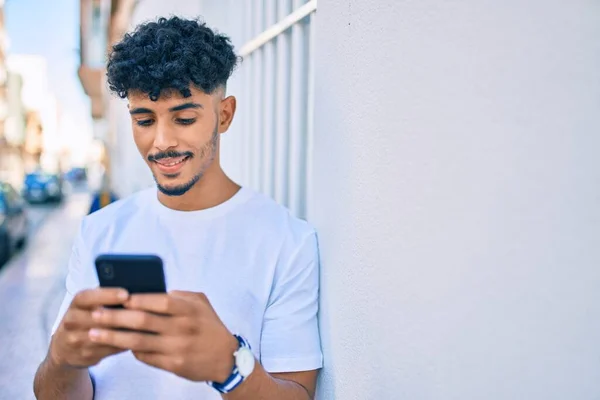 若いアラブ人男笑顔幸せな使用してスマートフォンの壁にもたれ — ストック写真