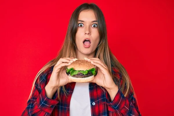 Piękna Biała Kobieta Jedząca Smacznego Klasycznego Burgera Przestraszonego Zszokowanego Zaskakującą — Zdjęcie stockowe