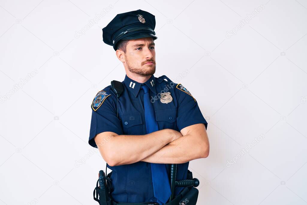 Young caucasian man wearing police uniform looking to the side with arms crossed convinced and confident 