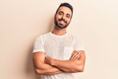 Gündelik kıyafetler giyen, kollarını kavuşturup kameraya gülümseyen genç İspanyol adam. pozitif kişi. 