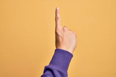 İzole edilmiş sarı arka planda parmaklarını gösteren beyaz bir gencin eli işaret parmağı kullanarak bir numarayı sayıyor, fikir ve anlayış gösteriyor.