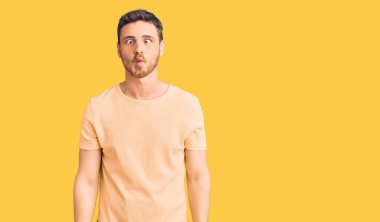 Ayılı yakışıklı genç adam gündelik sarı tişört giyiyor dudaklarıyla balık suratı yapıyor, çılgınca ve komik bir jest. Komik ifade. 