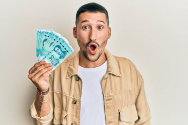 50 Yuan 'lık Çin banknotları tutan yakışıklı adam ağzı açık kalmış, korkmuş ve hayrete düşmüş. 