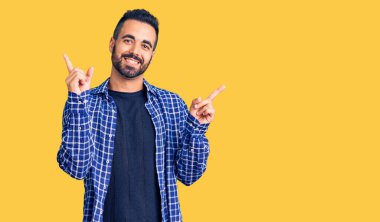 Gündelik kıyafetler giyen, kendine güvenen, parmaklarını farklı yönlere çeviren genç İspanyol adam. reklam için kopyalama alanı 