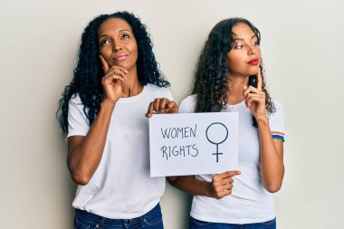 Afrika kökenli Amerikalı anne ve kız ellerinde kadın hakları afişi, ciddi bir yüz çene üstüne el ele sorusu, kafa karıştırıcı bir fikir. 