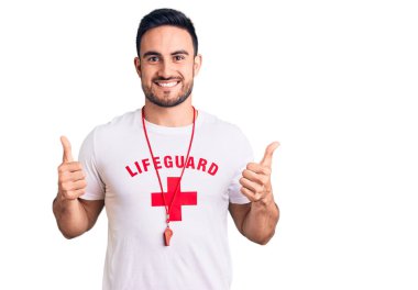 Cankurtaran üniforması giyen yakışıklı bir adam. Elleriyle olumlu jest yapıyor. Gülümsüyor ve mutlu. Neşeli ifade ve kazanan jest. 