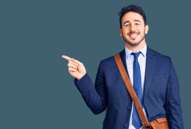 Genç İspanyol takım elbiseli ve deri çantalı adam gülümsüyor. 