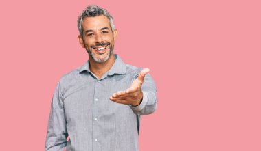 Orta yaşlı, gri saçlı, günlük kıyafetler giyen, gülümseyen, dostça el sıkışan bir adam. başarılı iş. 