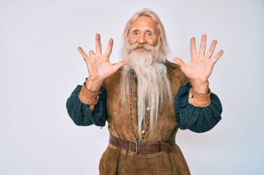 Gri saçlı, uzun sakallı, Viking kostümü giyen ve parmaklarını on numara gösteren yaşlı, kendinden emin ve mutlu bir adam.. 