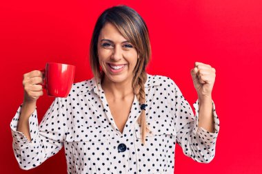 Genç ve güzel bir kadın kahve fincanı içerken gururla bağırıyor, zaferi kutluyor ve kollarını kaldırarak çok heyecanlanıyor. 