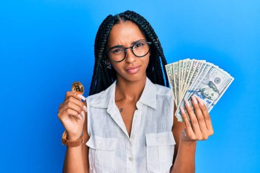 Sanal para birimi Bitcoin ve dolarları elinde tutan güzel İspanyol kadın, şüpheli ve alaycı görünüyor, ağzı açık kalmış. 